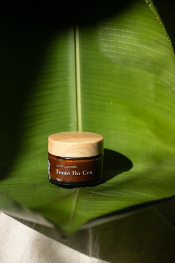 Crema corporal en frasco de vidrio sobre una hoja de banano