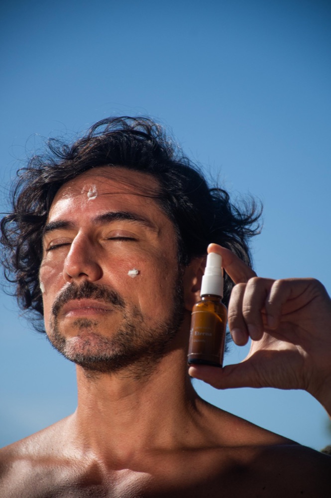 Persona aplicándose crema facial natural al aire libre