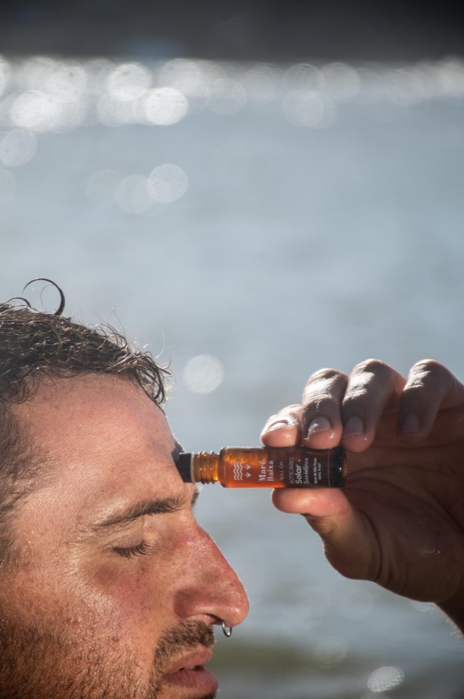Hombre aplicándose un roll-on de aromaterapia frente al mar