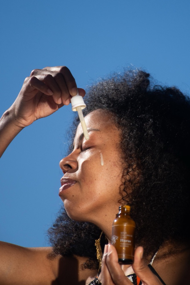 Mujer aplicándose sérum facial al aire libre
